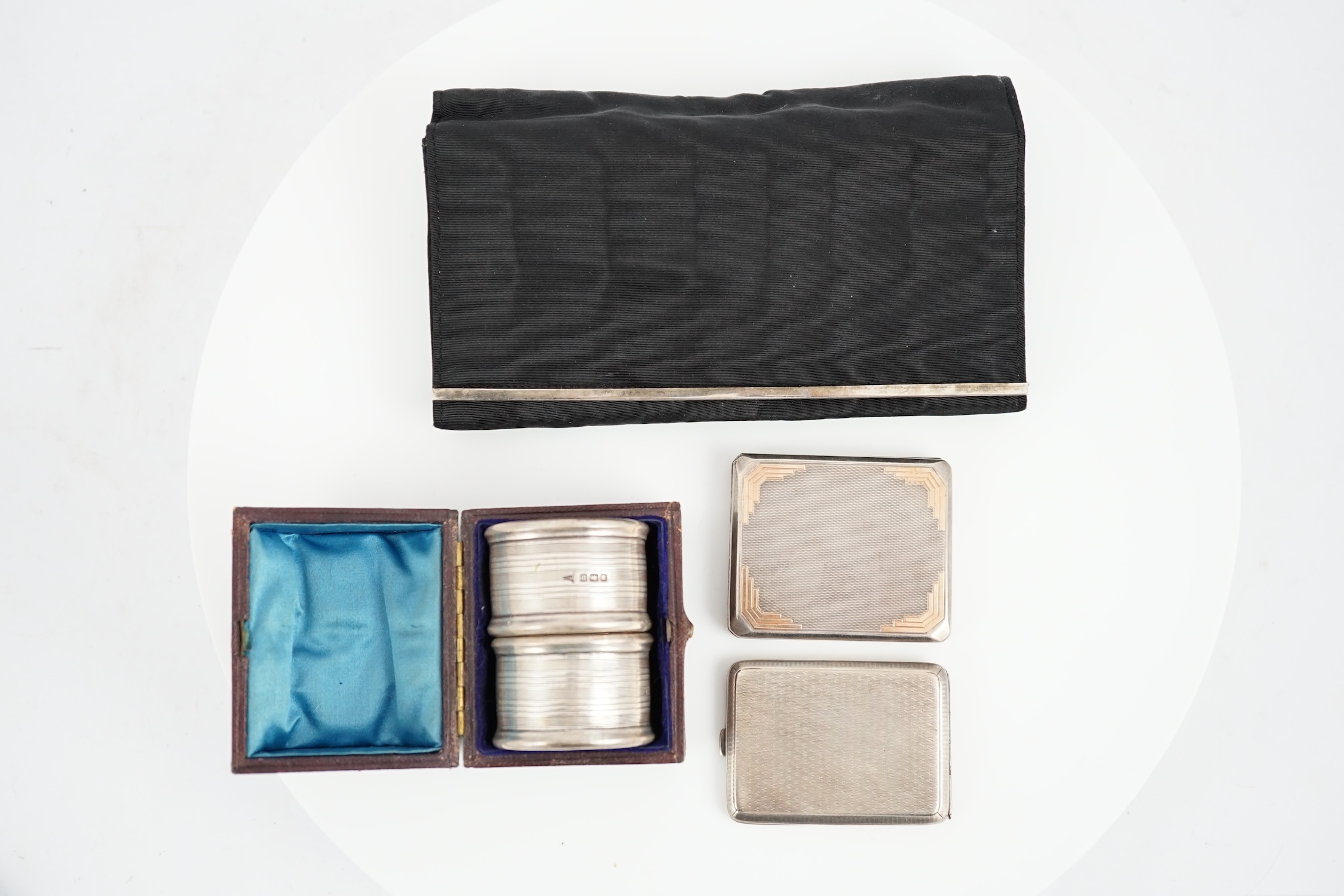 An Art Deco engine turned silver match sleeve by Asprey & Co, Birmingham, 1933, 6cm, together with one other silver match sleeve, a cased pair of silver napkin rings and a continental silver mounted four piece vanity set